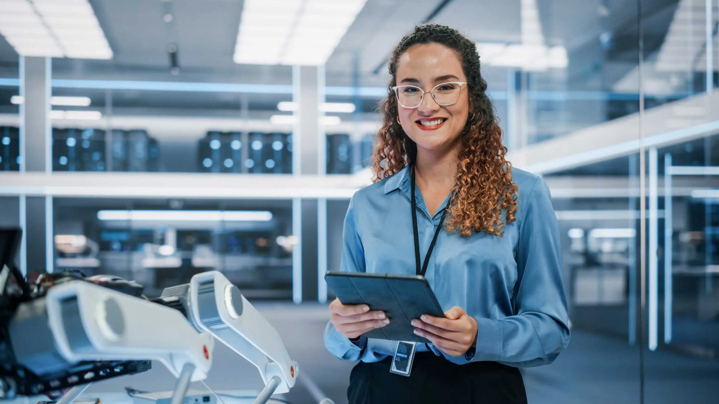 Woman smiling in a tech manufacturing facility, representing career training and job opportunities through Workforce Solutions Capital Area