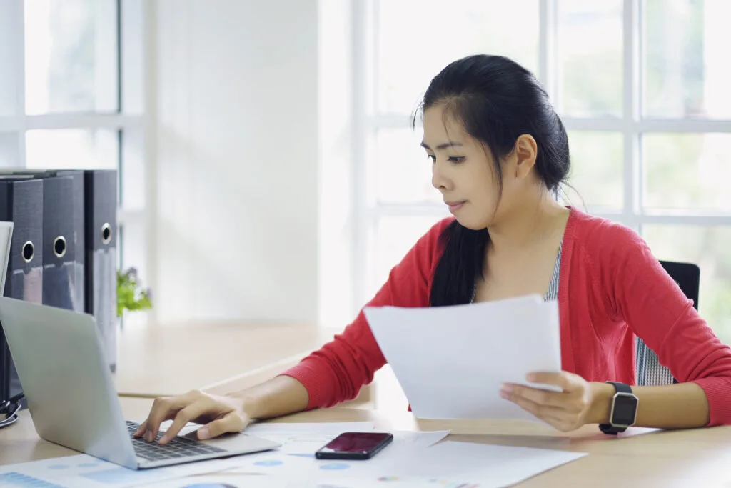 Parent reviewing child care payment documents at a laptop, representing quality programs through Workforce Solutions Capital Area