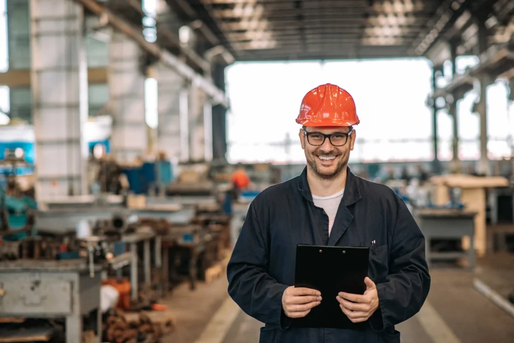 Worker in a hard hat smiling in a workshop, representing paid apprenticeship programs available through Workforce Solutions Capital Area