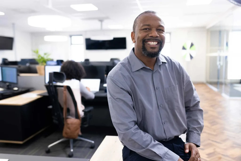 Professional smiling at his desk in an office, representing career planning and exploration resources from Workforce Solutions Capital Area