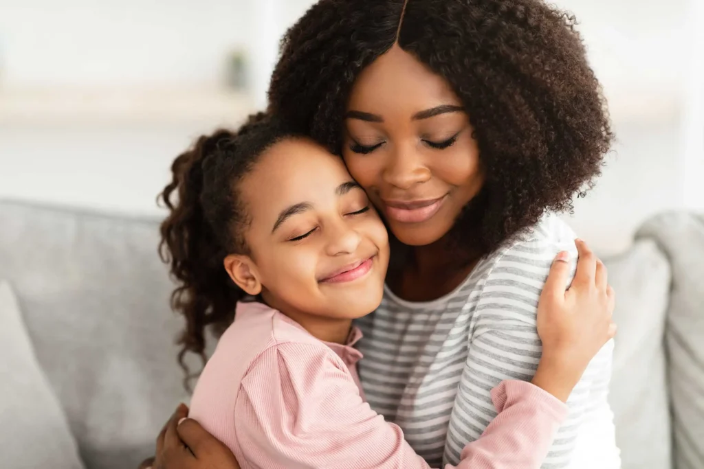 Mother and daughter embracing on the couch, representing families applying for child care scholarship assistance through Workforce Solutions Capital Area