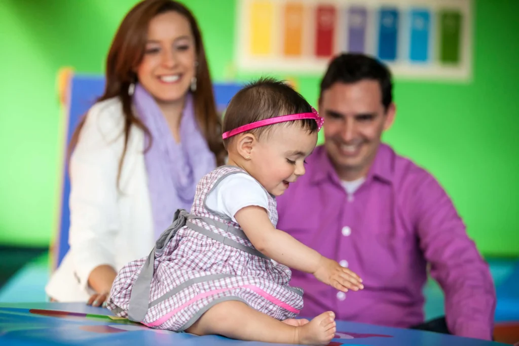 Parents smiling as their baby plays at a child care center, representing the 400+ provider options available through Workforce Solutions Capital Area